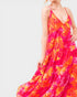 Woman wearing a vibrant floral dress on a plain background