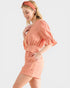 Woman wearing a peach-colored dress with a matching headband on a white background