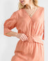 Woman wearing a peach-colored dress with a belt on a white background