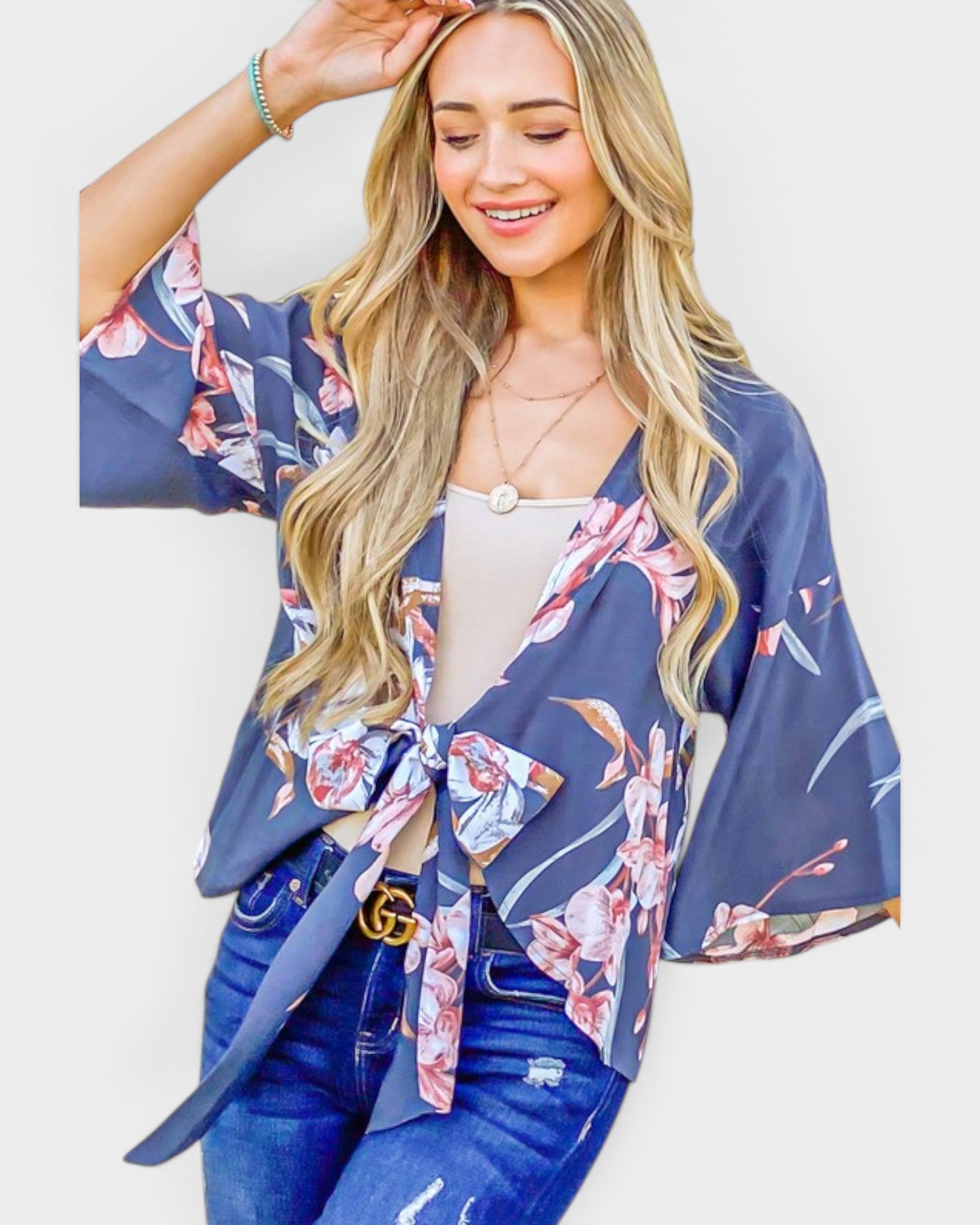 Woman wearing a blue floral kimono over a white top and jeans on a light background