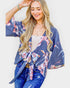 Woman wearing a blue floral kimono over a white top and jeans on a light background