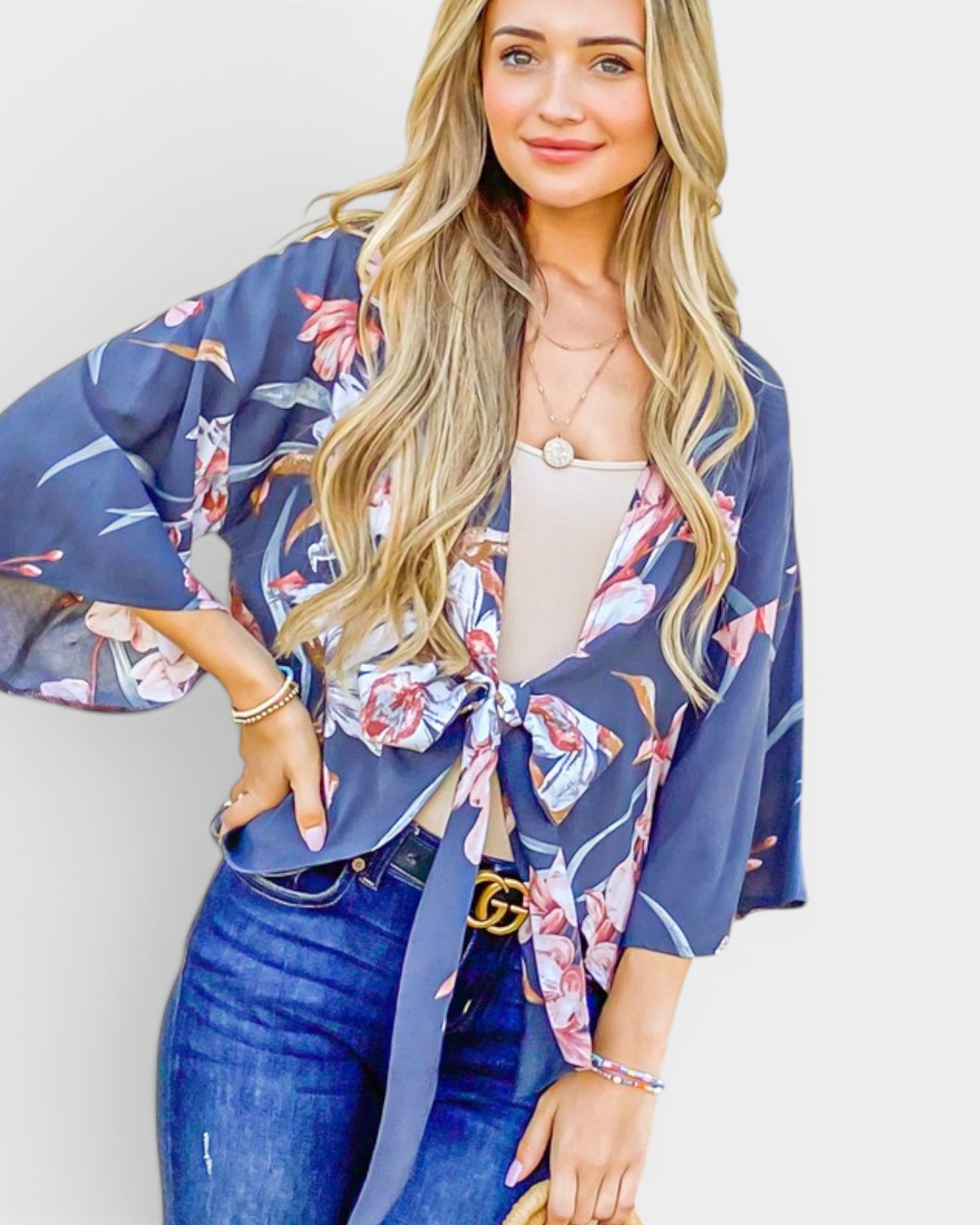 Woman wearing a floral kimono over a white top and blue jeans against a white background