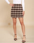 Person wearing a brown and beige plaid skirt on a beige background