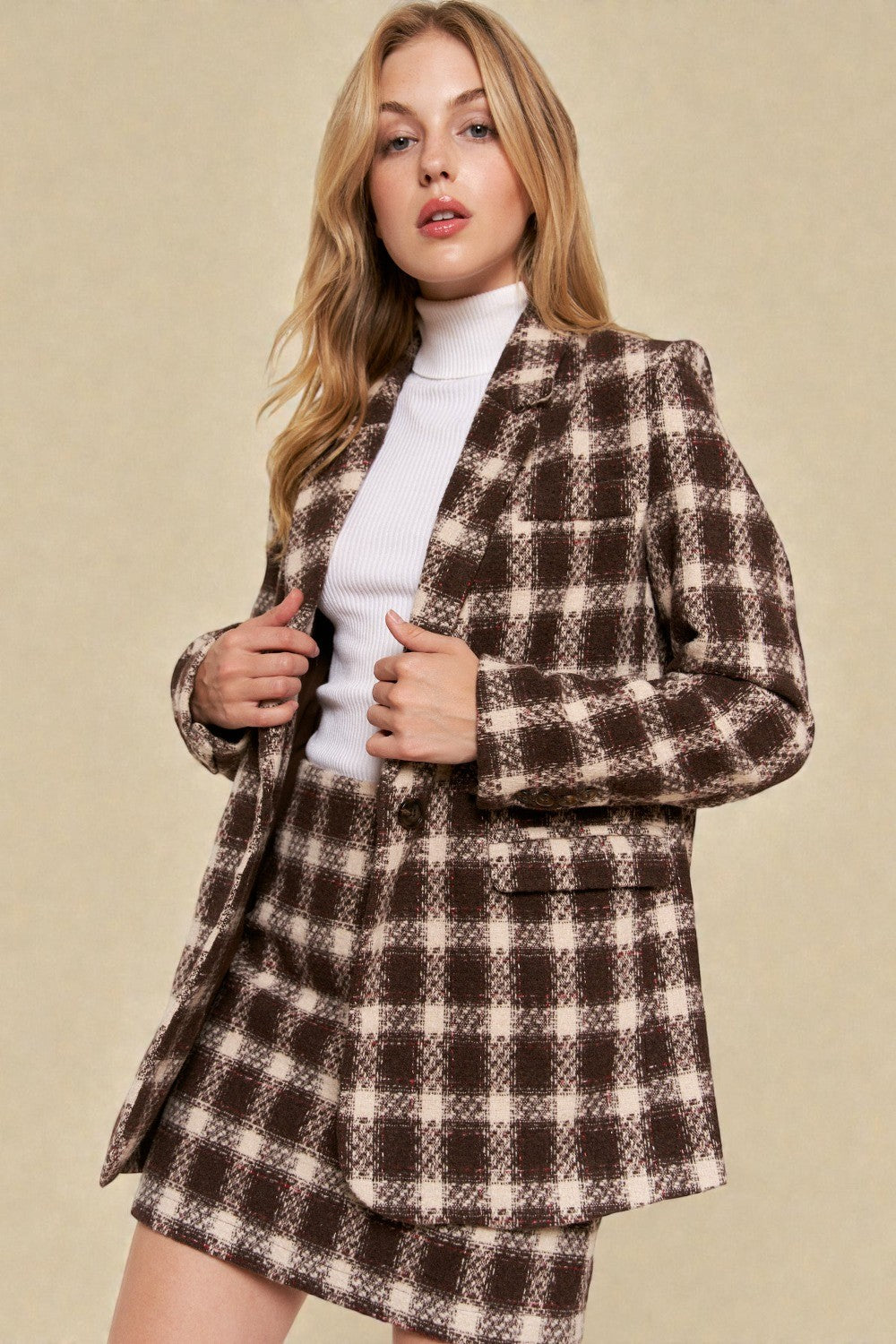 Woman wearing a brown and white checkered suit against a beige background