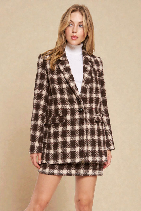 Woman wearing a plaid coat and skirt set against a beige background