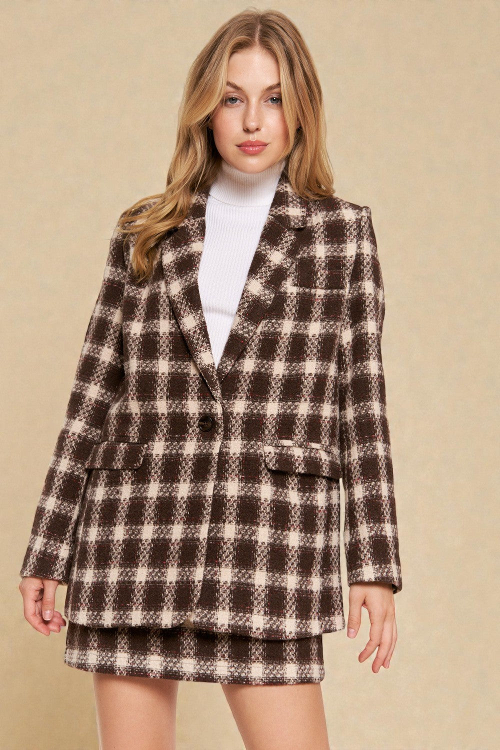 Woman wearing a brown and beige checkered suit against a beige background