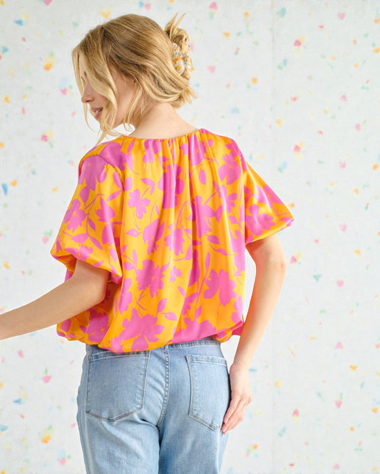 Woman wearing a colorful blouse with a pattern against a multicolored polka dot background