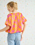 Woman wearing a colorful blouse with a pattern against a multicolored polka dot background