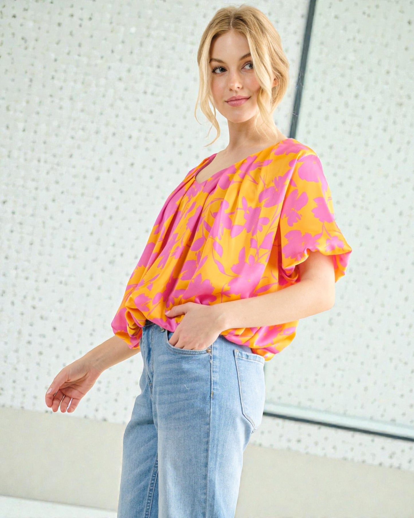Woman wearing a colorful blouse with a white textured wall background
