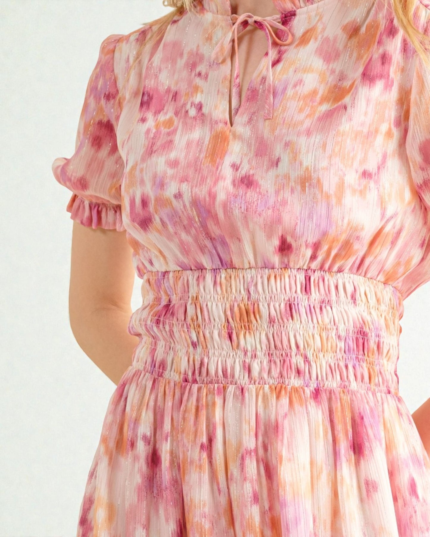 Woman wearing a floral dress with pink and orange colors on a white background