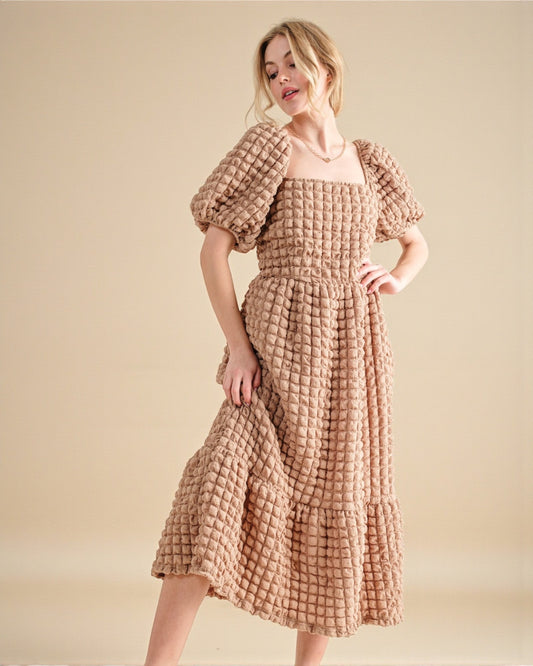 Woman wearing a textured dress with matching bolero on a beige background