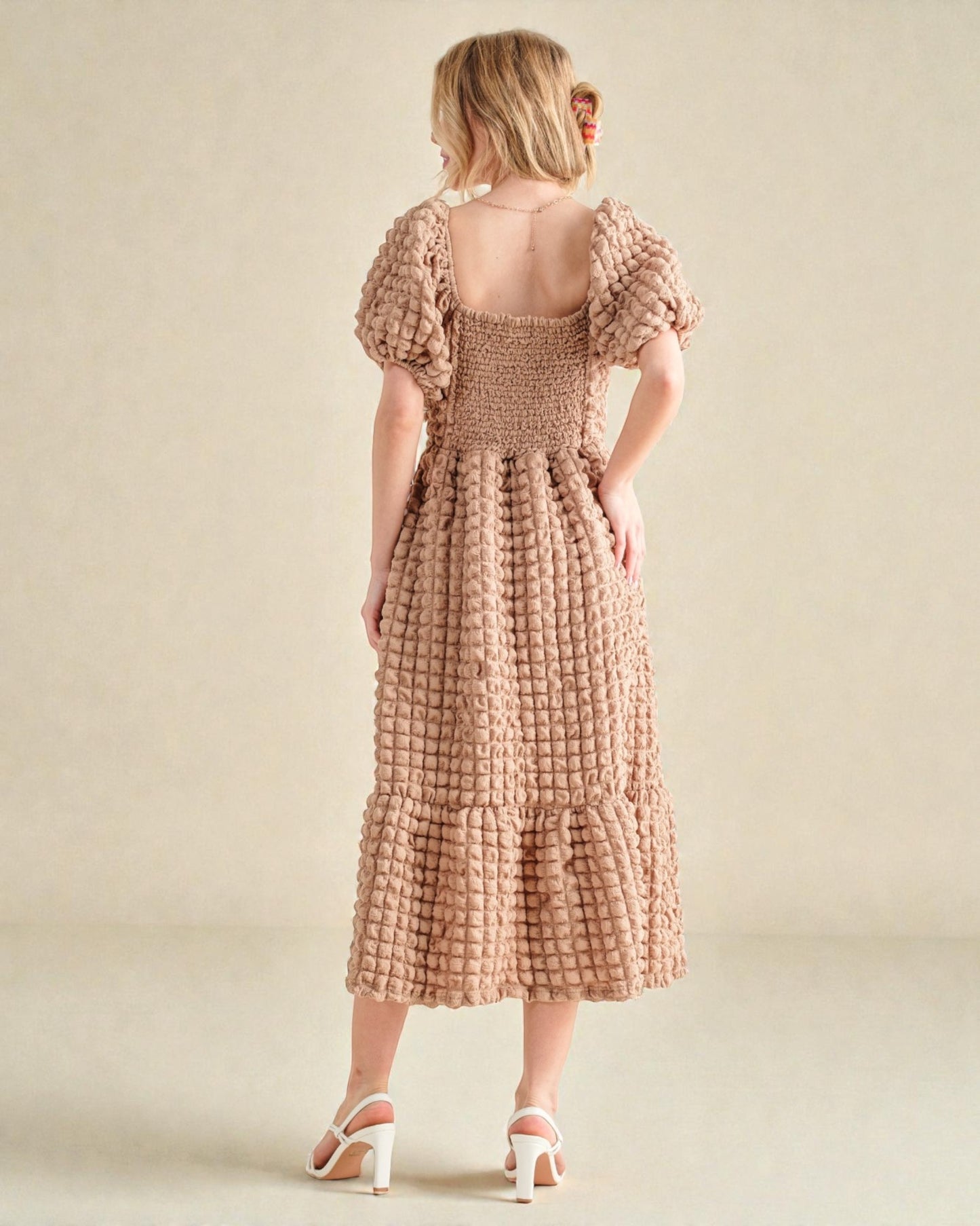 Woman wearing a patterned dress on a plain background