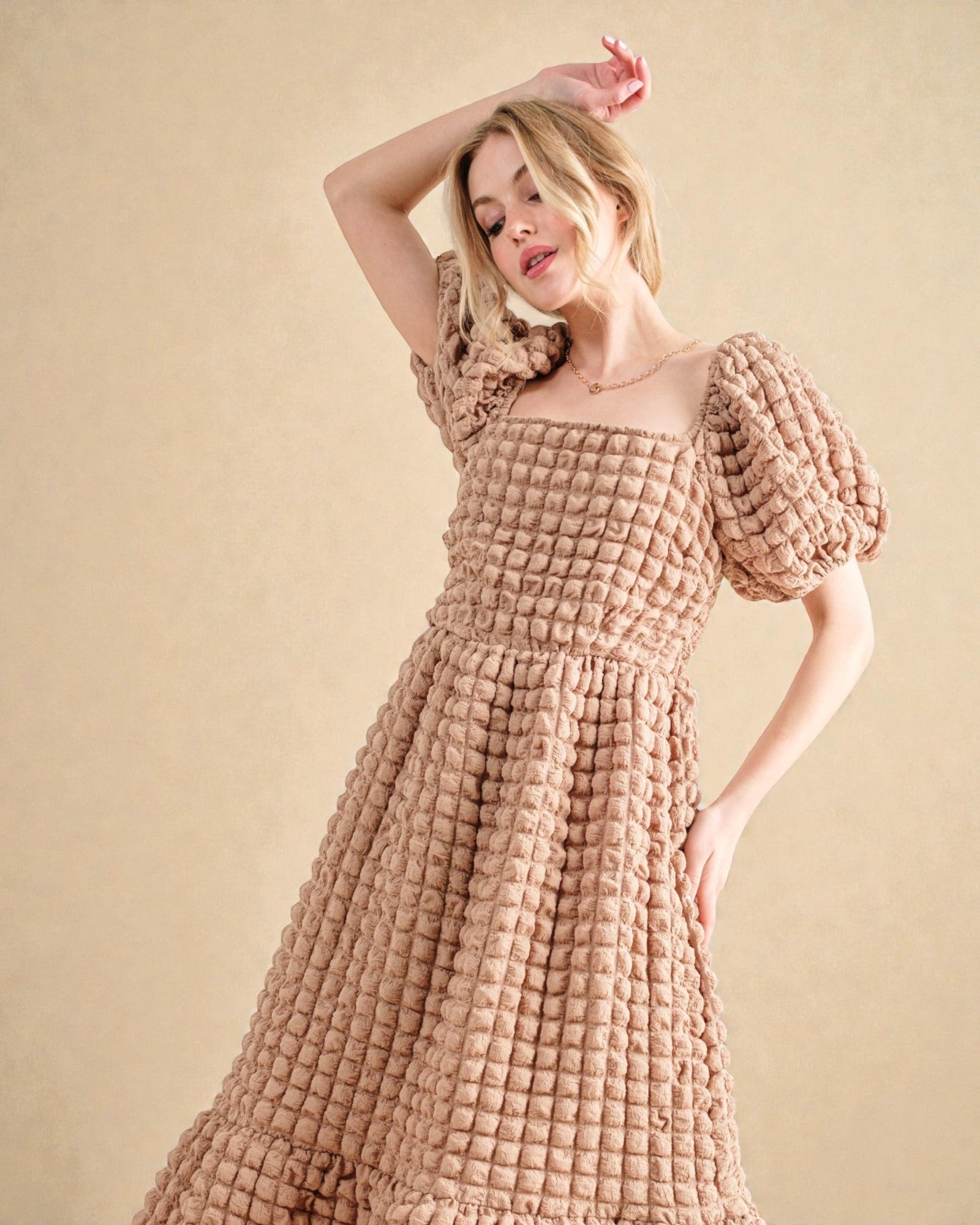 Woman wearing a textured brown dress against a beige background