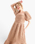 A woman modeling a textured, chunky knit midi dress in a warm beige color, featuring puff sleeves and a square neckline, set against a plain white studio background.