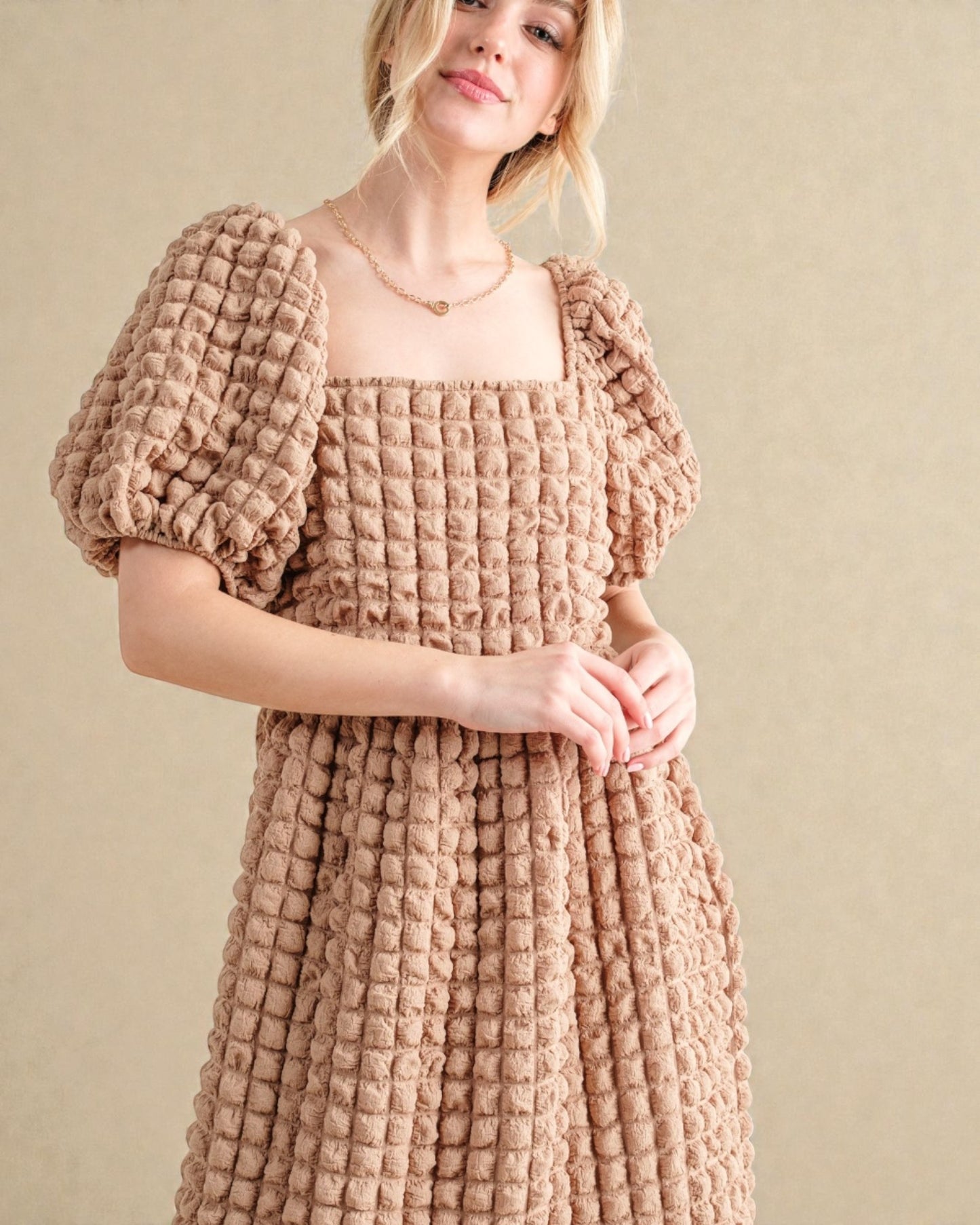 Woman wearing a textured pink dress against a beige background