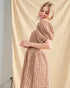 Woman wearing a textured beige dress against a beige curtain