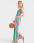 Woman wearing a colorful striped dress holding a woven bag on a white background