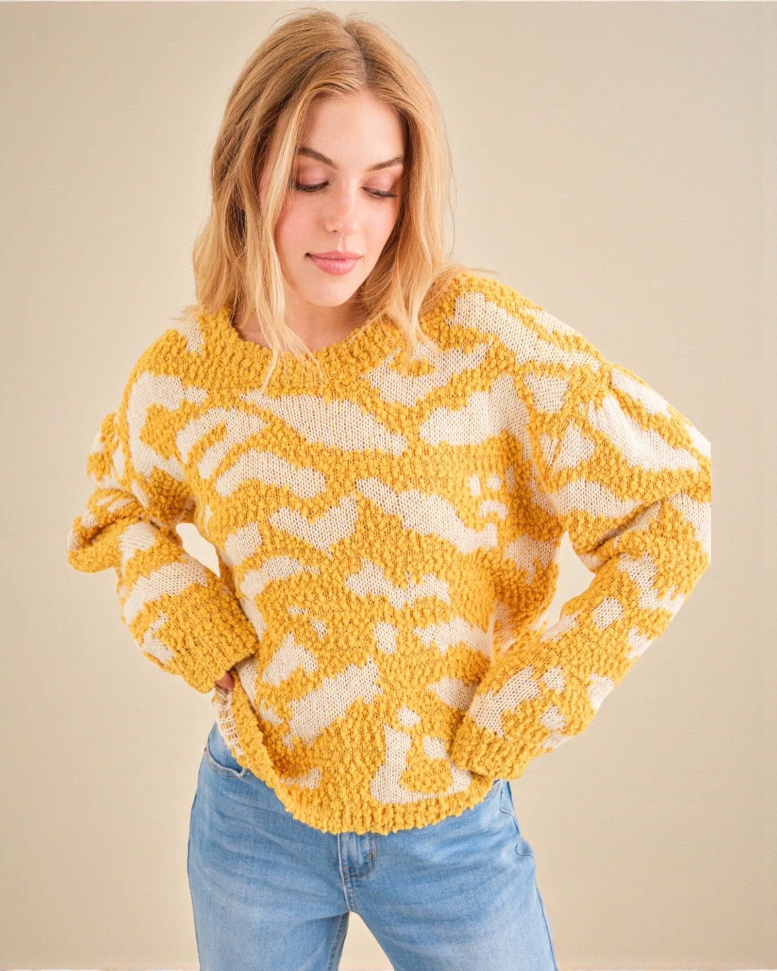 Woman wearing a yellow and white patterned sweater against a beige background