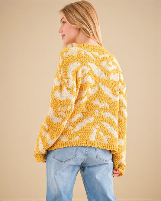 Woman wearing a yellow and white patterned sweater against a beige background
