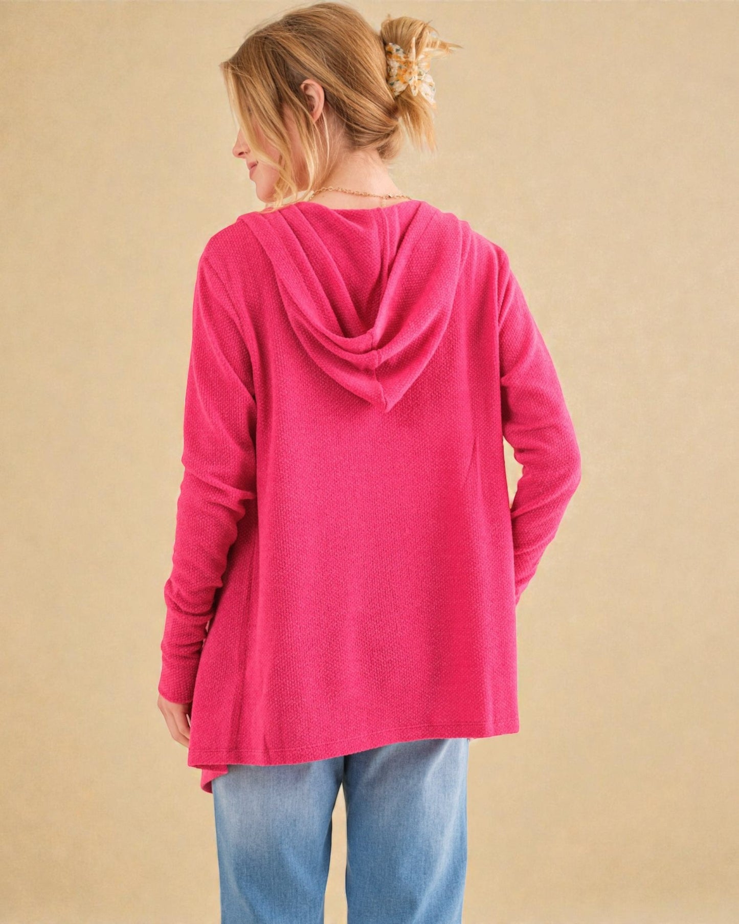 Person wearing a pink hoodie on a beige background