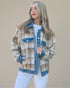 Woman wearing a plaid jacket with denim trim on a beige background