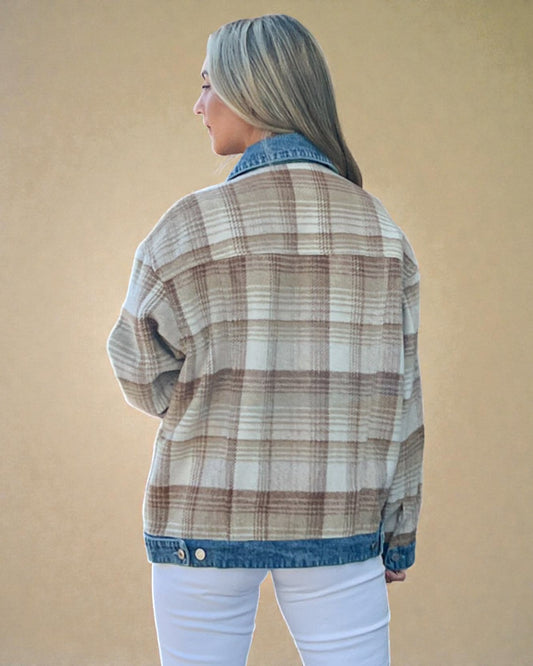 Person wearing a plaid shirt with denim collar against a beige background