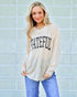 Woman wearing a 'Grateful' shirt against a light brick wall