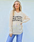 Woman wearing a beige sweatshirt with 'GRATEFUL' text against a light blue background