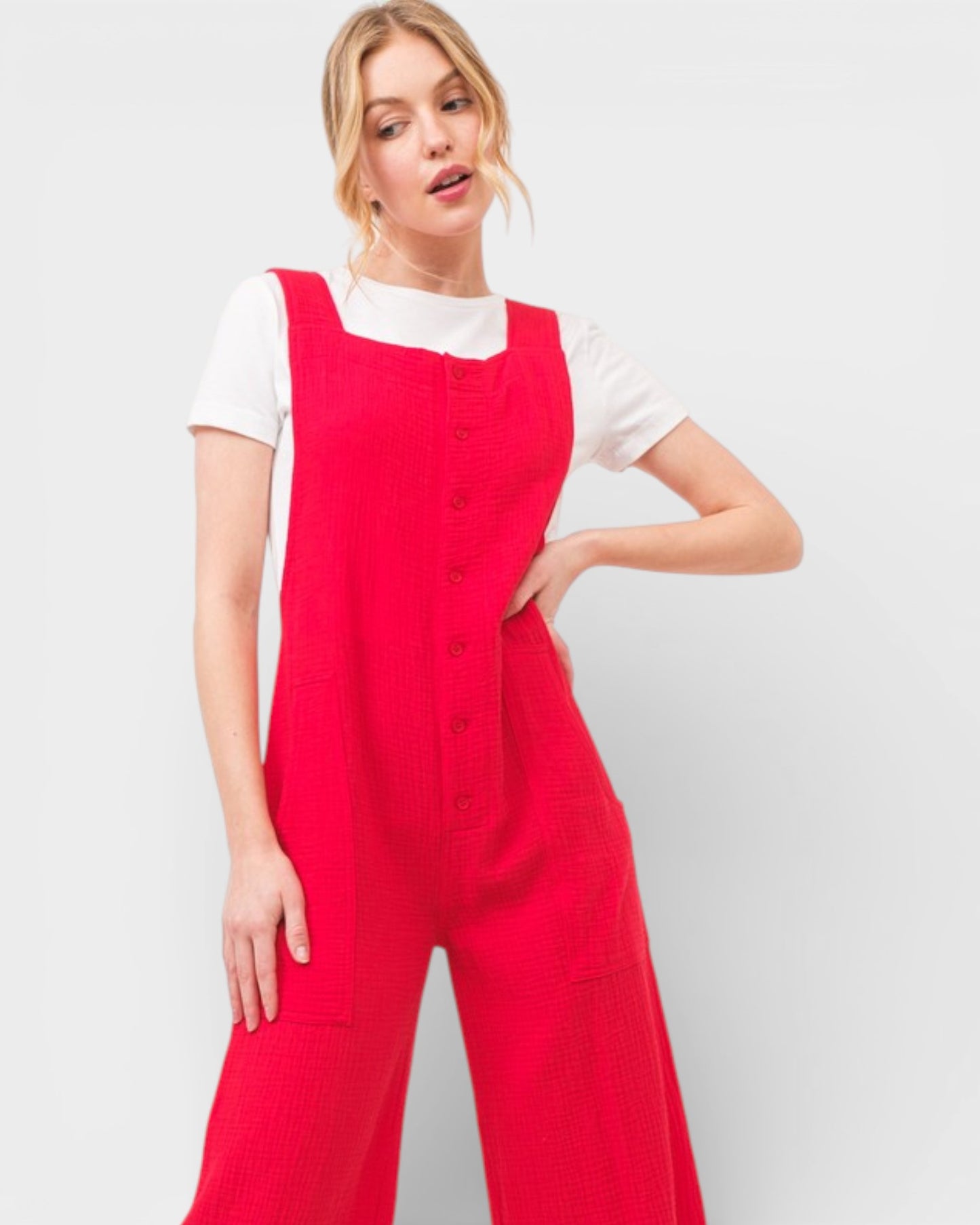Woman wearing a red jumpsuit over a white shirt on a light gray background