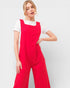 Woman wearing a red jumpsuit over a white shirt on a light gray background