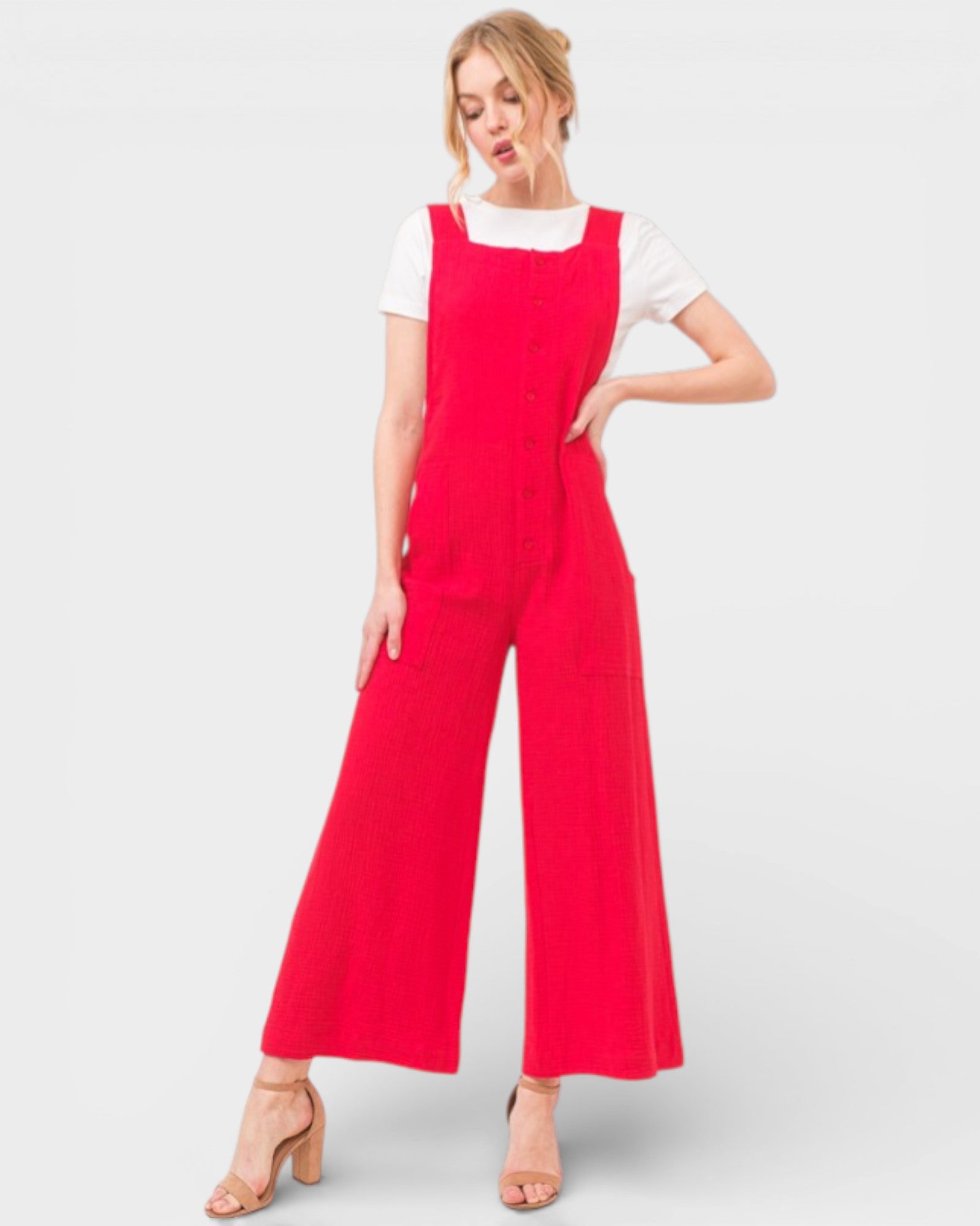 Woman wearing a red jumpsuit over a white shirt on a light gray background