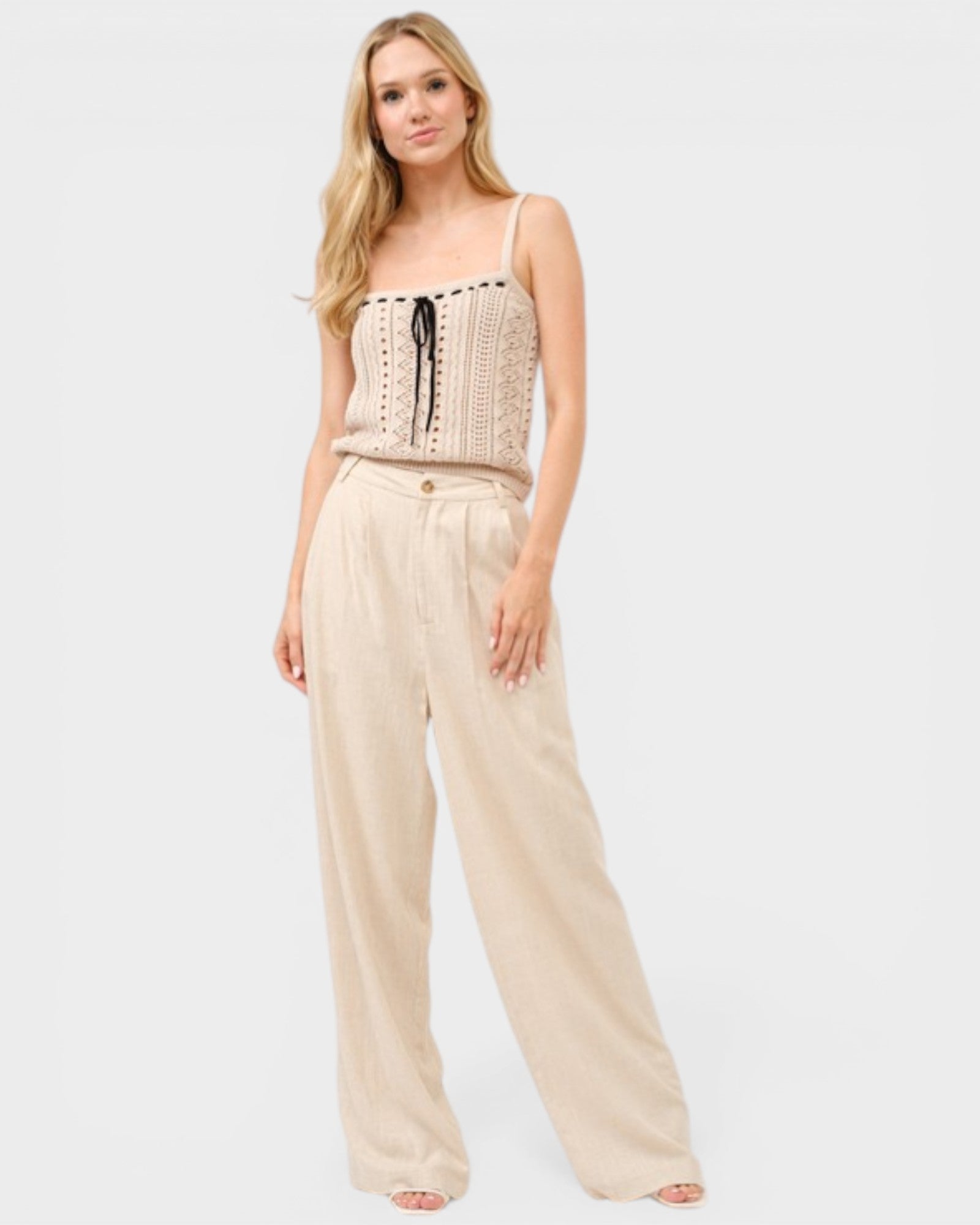 Woman wearing a beige sleeveless top and pants on a white background
