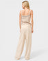 Woman wearing a beige crochet top and wide-leg pants on a white background