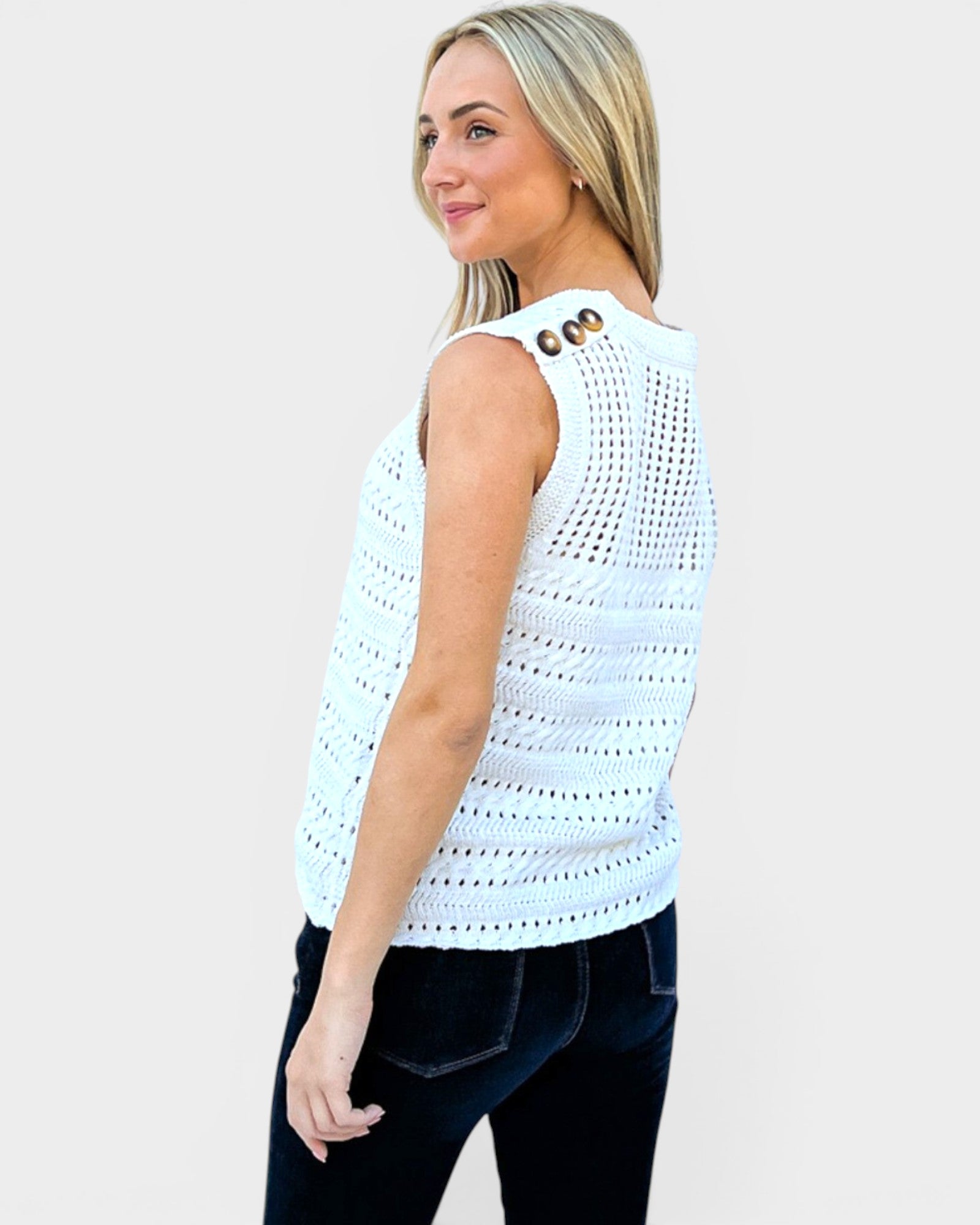 Woman wearing a light blue sleeveless crochet top on a plain background