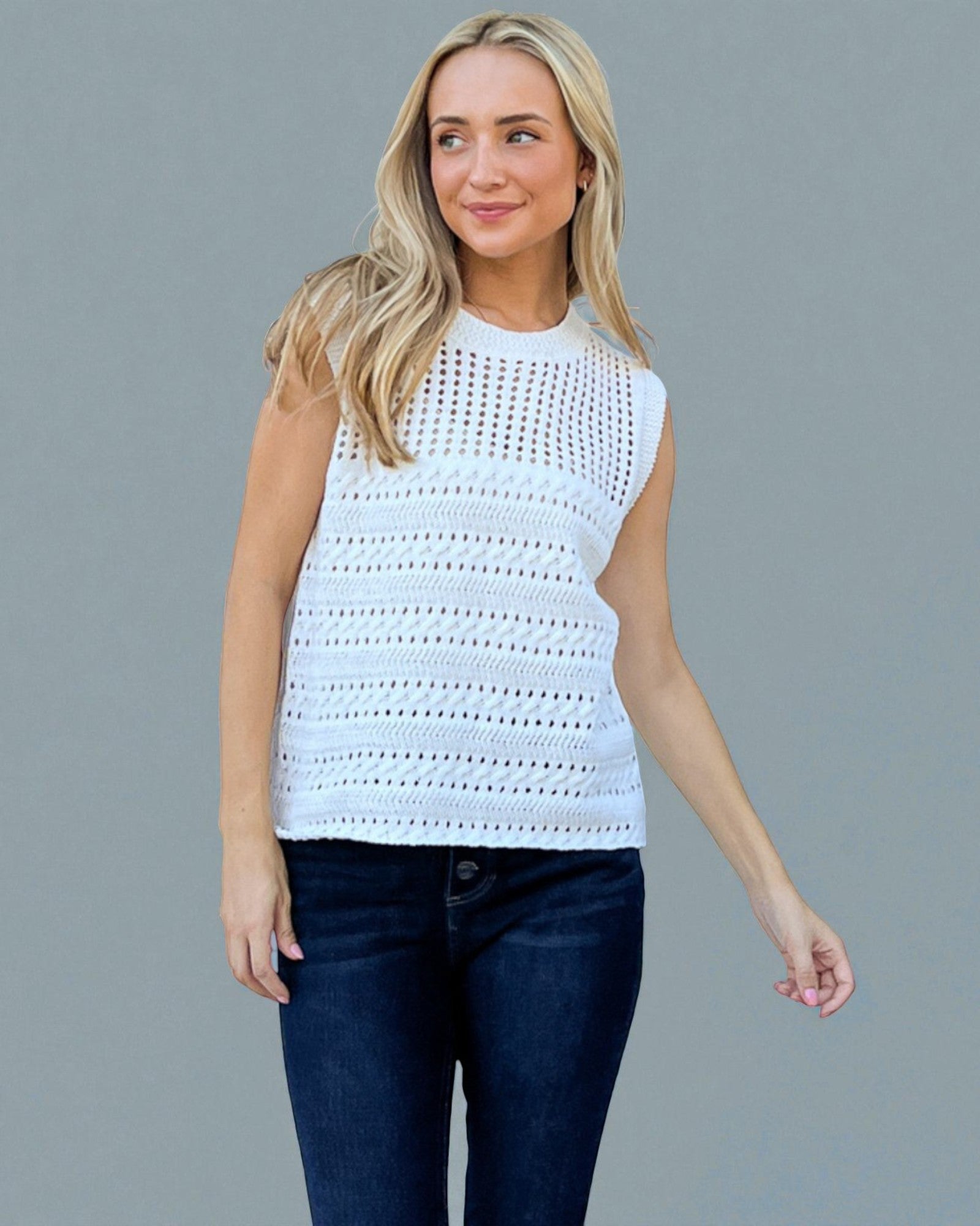 Woman wearing a sleeveless crochet top against a gray background