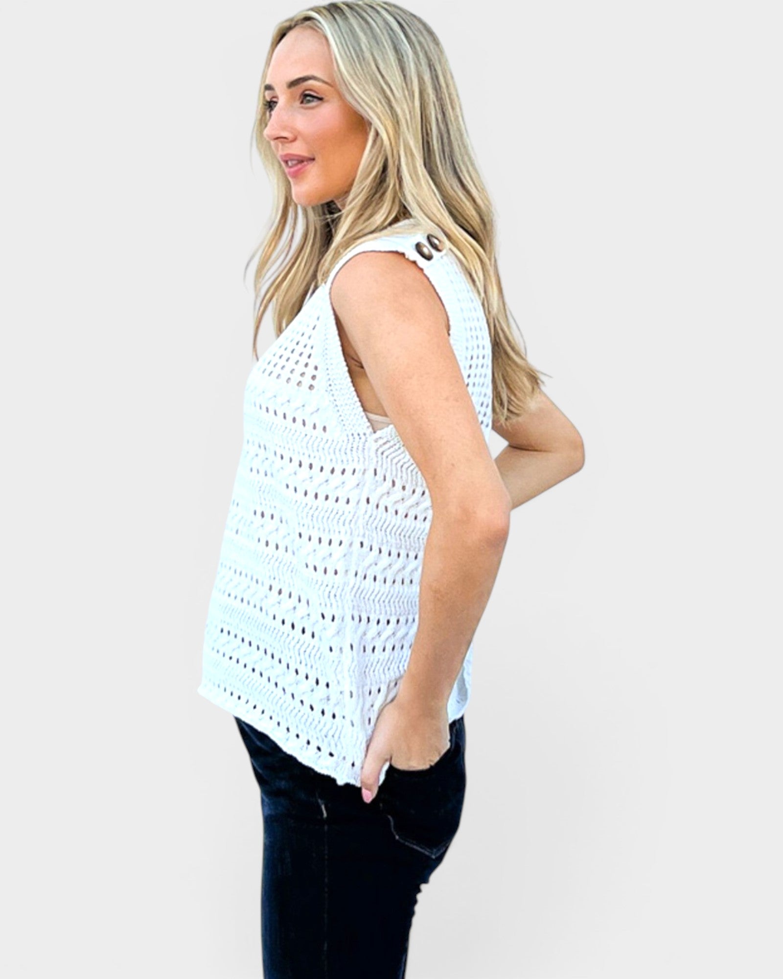 Woman wearing a light blue sleeveless crochet top against a plain background
