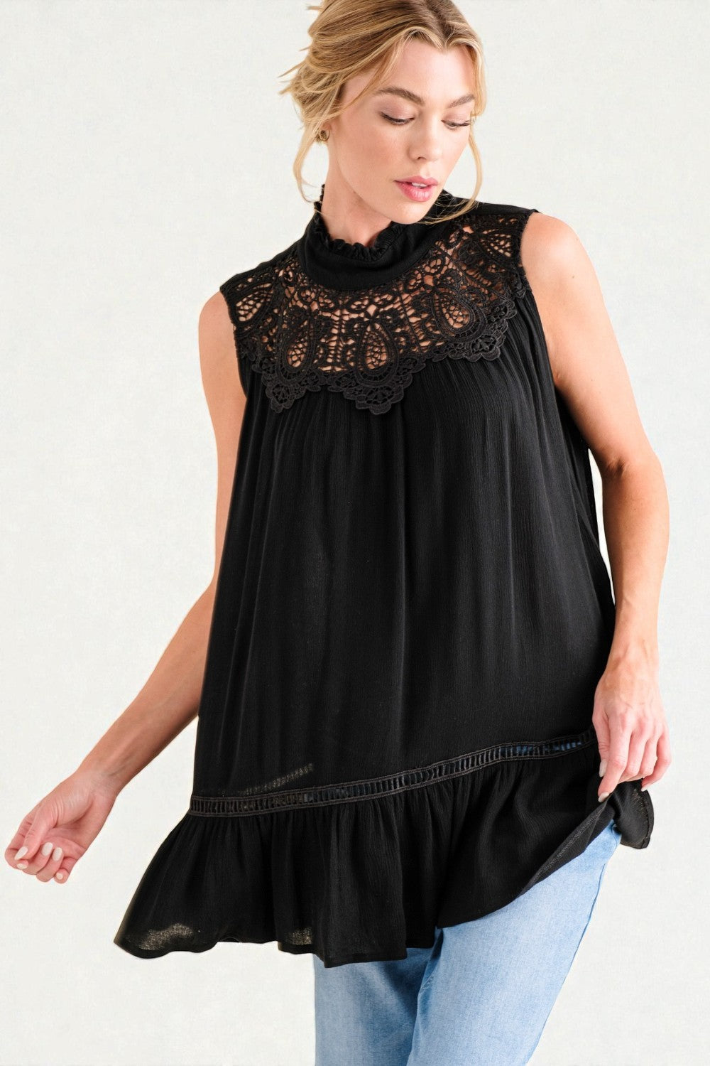 Woman wearing a black sleeveless top with lace details on a white background