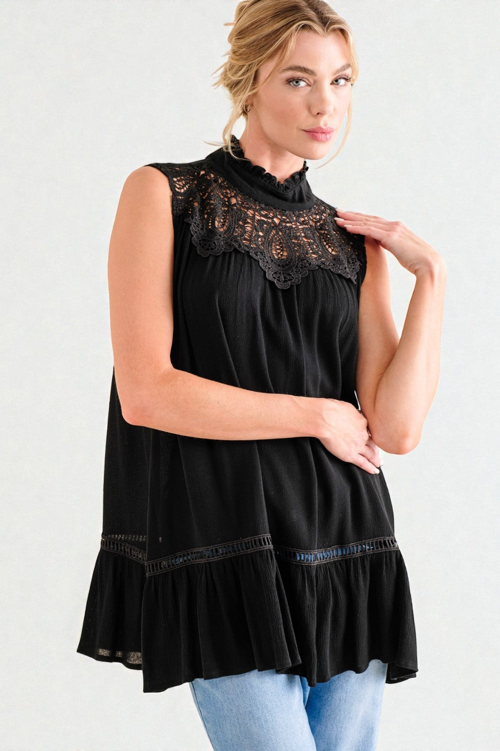 Woman wearing a black sleeveless top with lace details on a white background