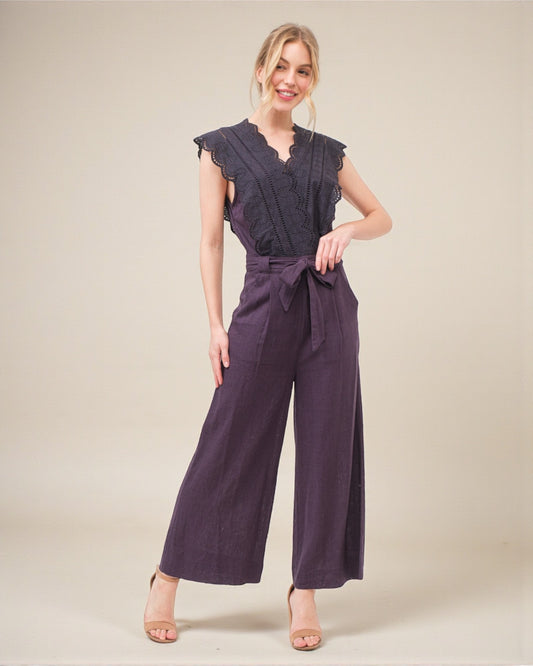 Woman wearing a purple jumpsuit on a plain background