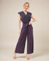 Woman wearing a purple jumpsuit on a plain background