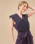 Woman wearing a dark purple top with lace details on a beige background