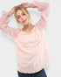 Woman wearing a light pink hoodie against a white background