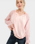 Woman wearing a light pink blouse with sheer sleeves on a white background