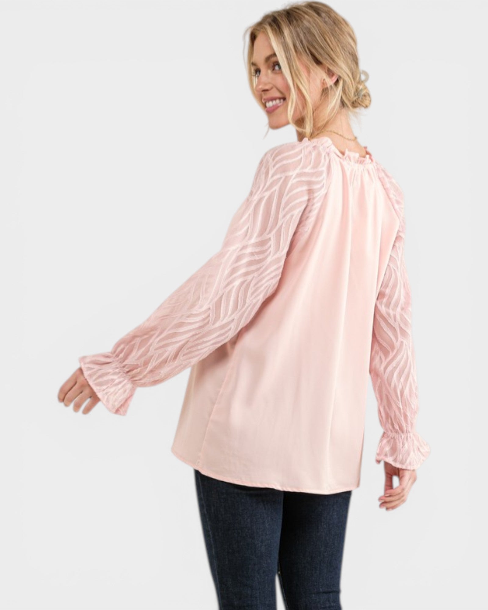 Woman wearing a light pink blouse with long sleeves on a white background