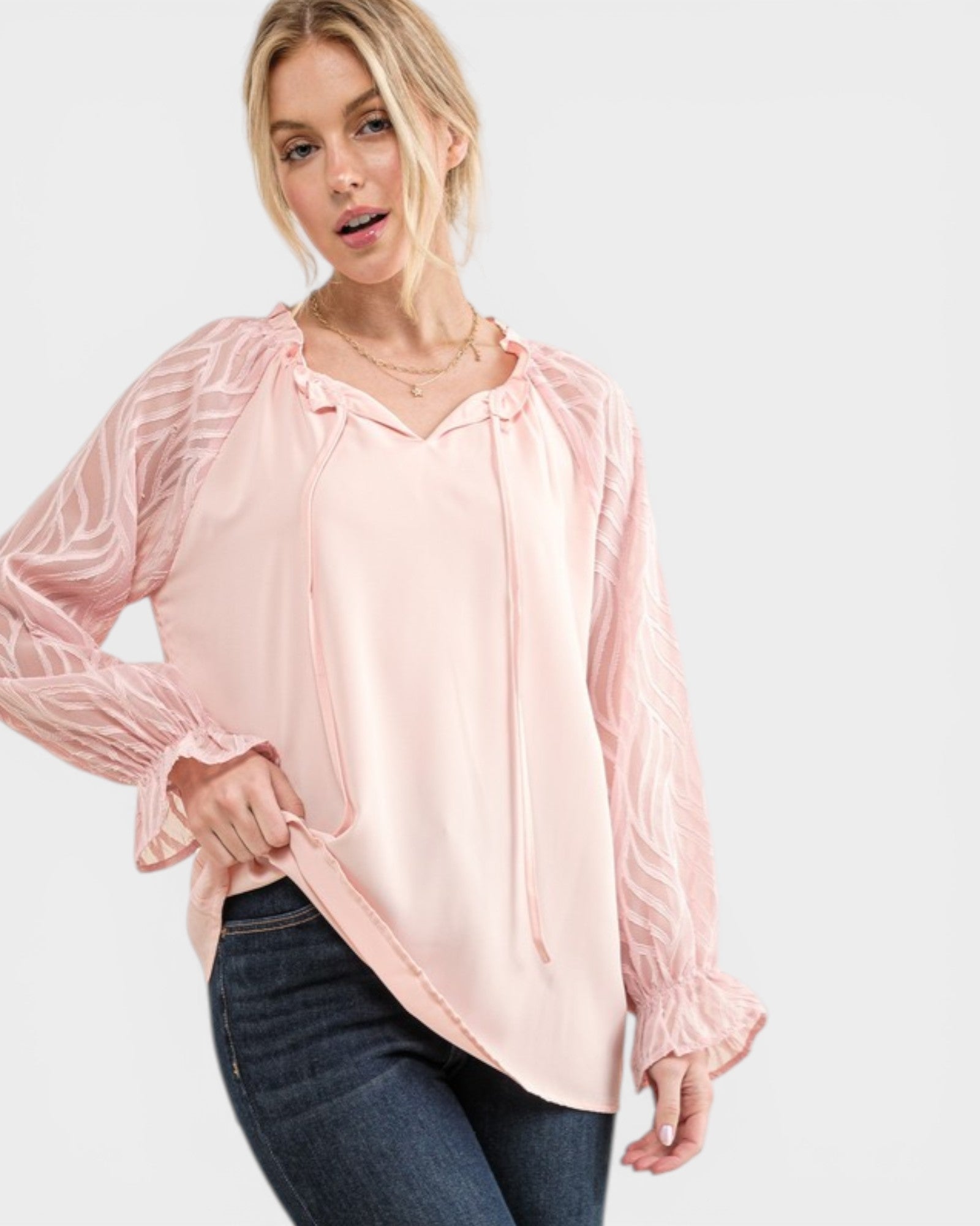 Woman wearing a light pink blouse with long sleeves on a white background