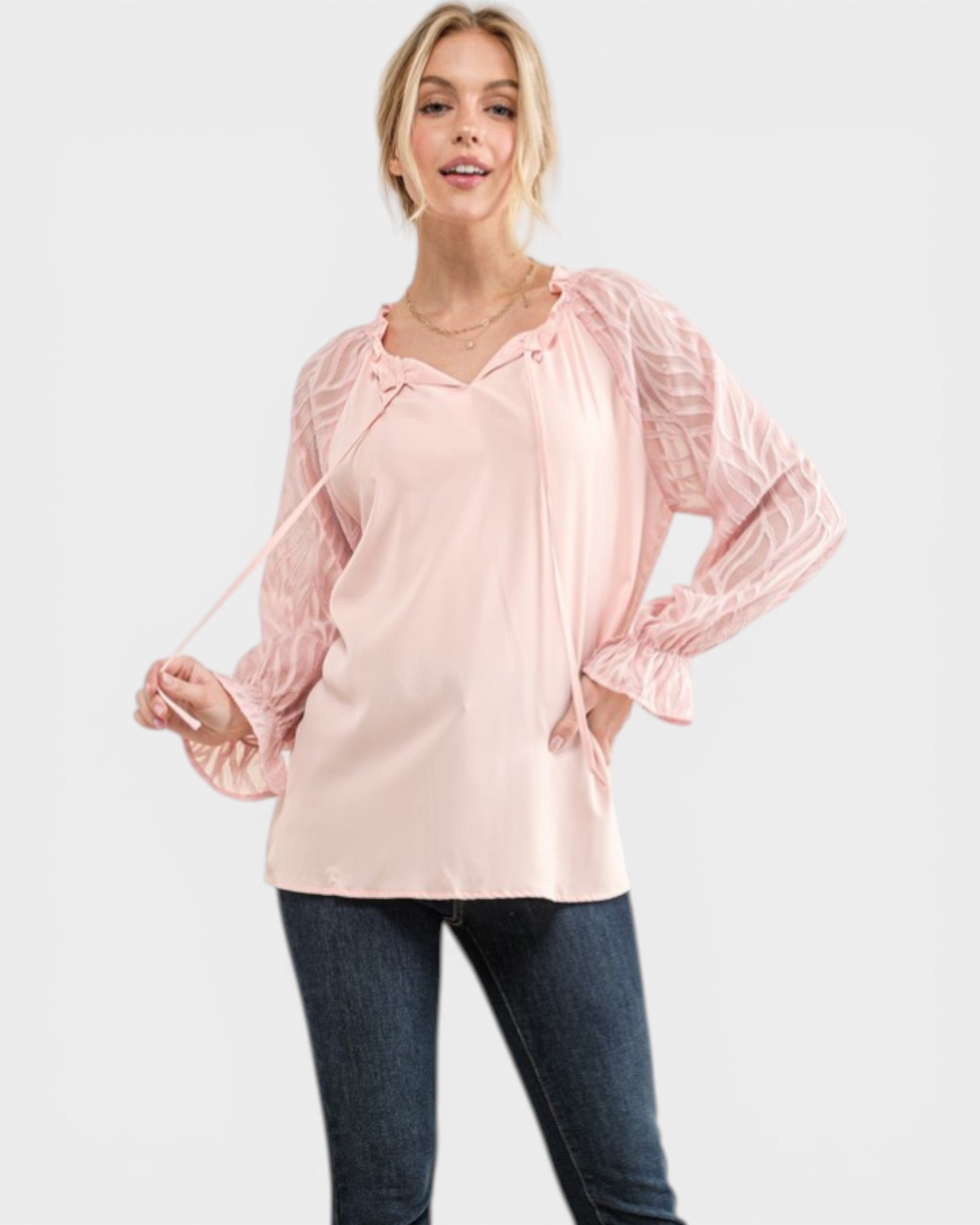 Woman wearing a light pink blouse with long sleeves on a white background
