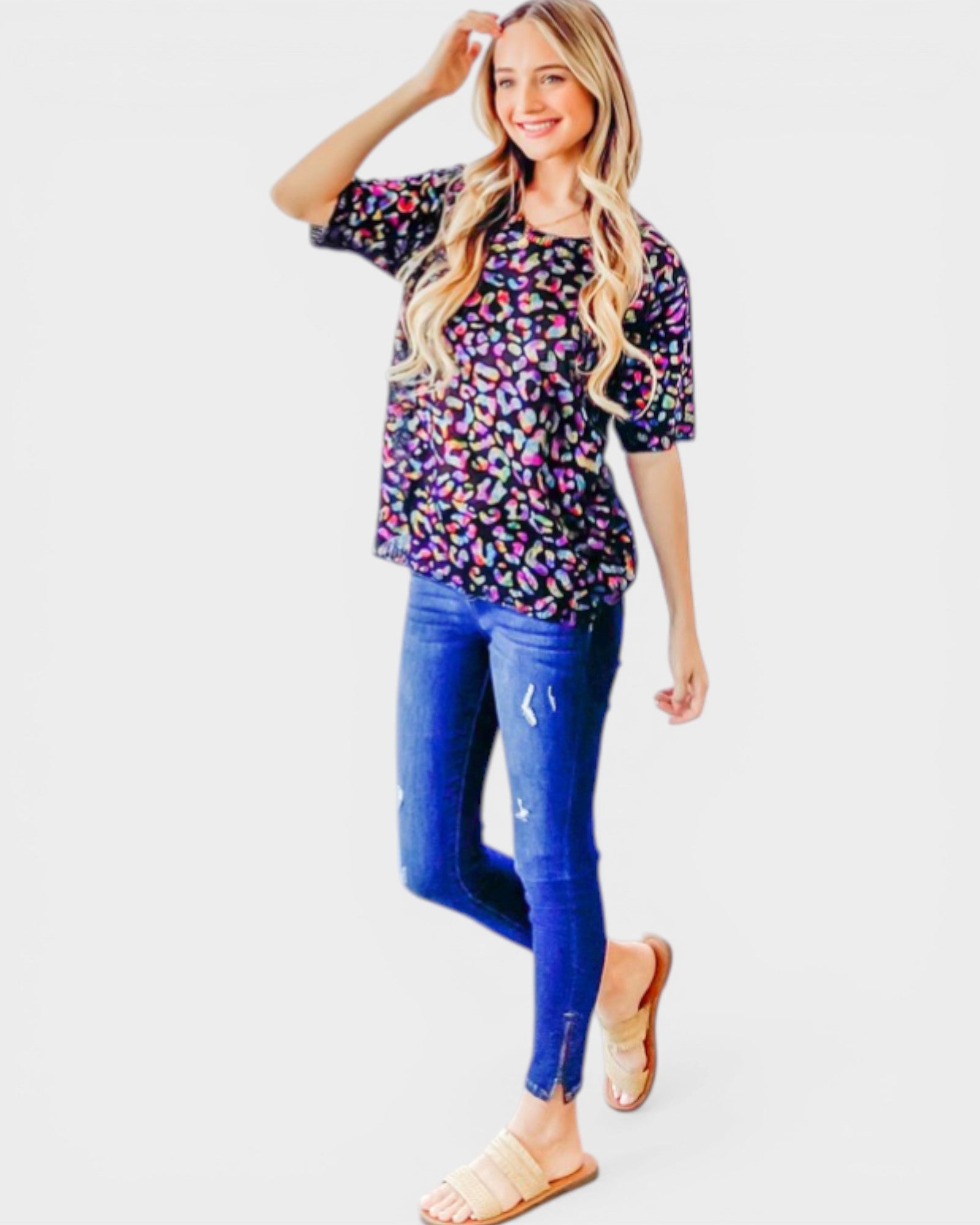 Woman wearing a colorful patterned top and blue jeans on a white background