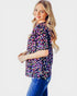 Woman wearing a colorful patterned shirt and blue jeans on a white background