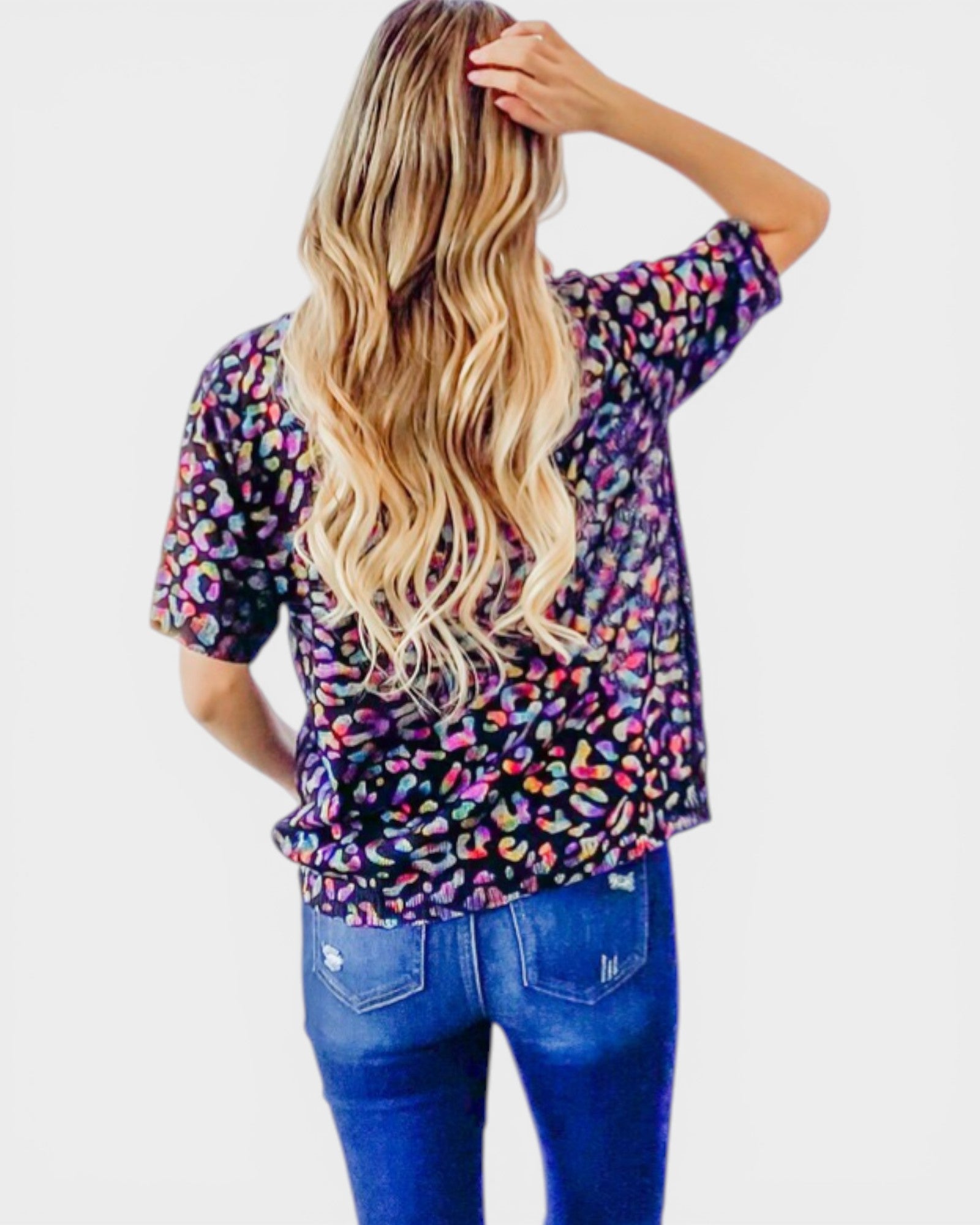 Person wearing a colorful patterned shirt and blue jeans on a white background