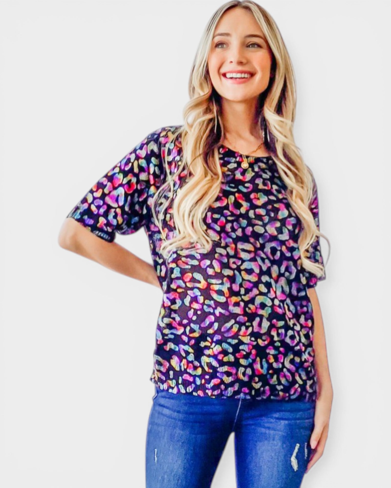 Woman wearing a colorful leopard print top against a white background